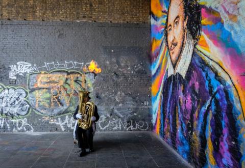Tuba player in front of Shakespeare mural